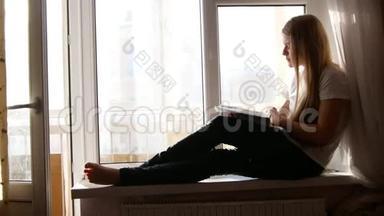 坐在窗台上翻书的漂亮金发女孩
